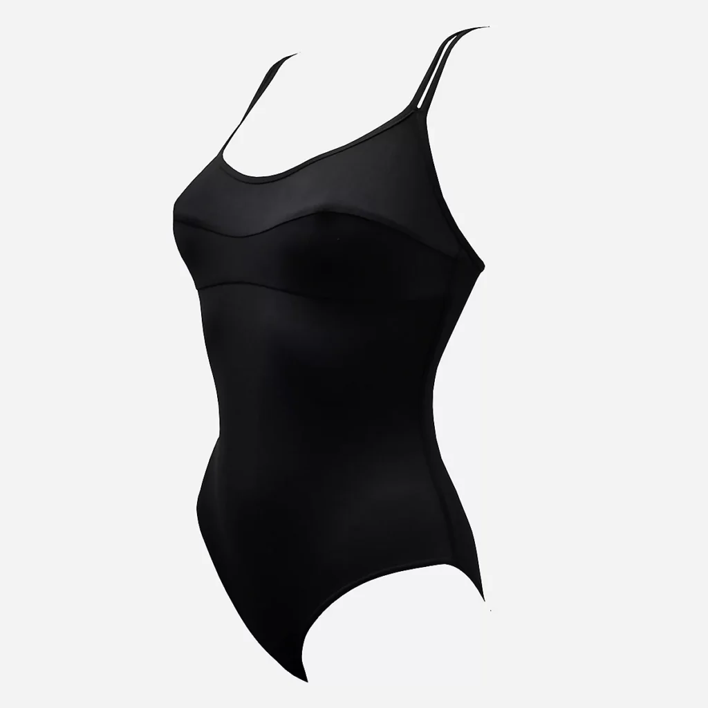 Maillot de bain 1 pièce menstruel Grain de Sable pour femme en bleu marine, design entièrement doublé avec bretelles réglables et plaque logo, porté par un mannequin sur une plage ensoleillée, mettant en avant son confort et sa protection discrète pour l'été.