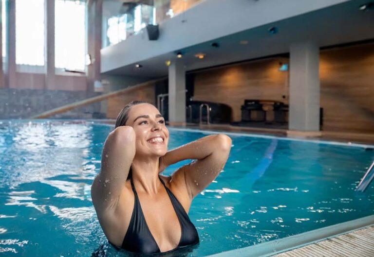 Nageuse aux cheveux longs au bord d'une piscine illustrant l'impact de la natation et du chlore sur la chevelure.